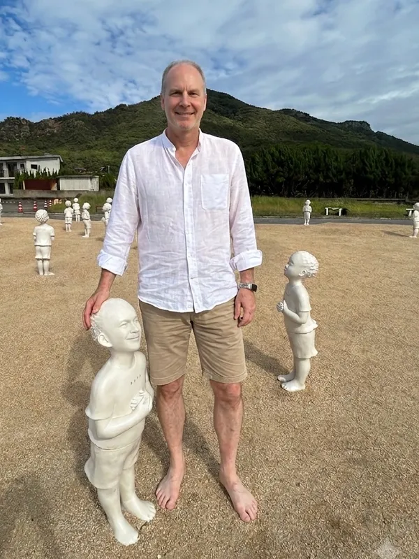 Derek kneeling beside one of the statues from Beyond the Border - Prayer on Teshima Island, Japan